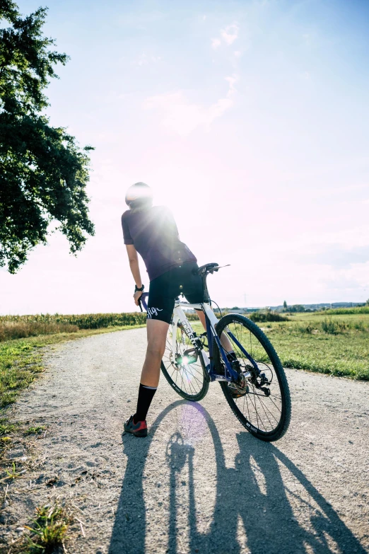 a woman is standing with her bike on a path