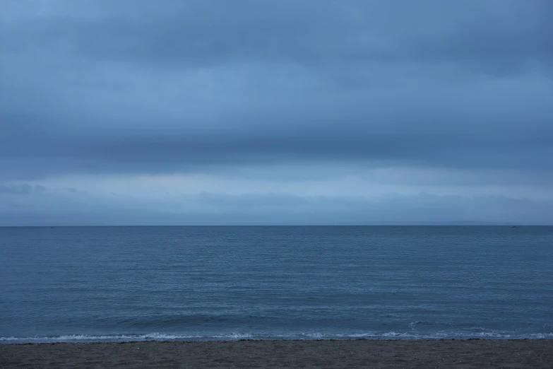 two people walk down the beach under an umbrella