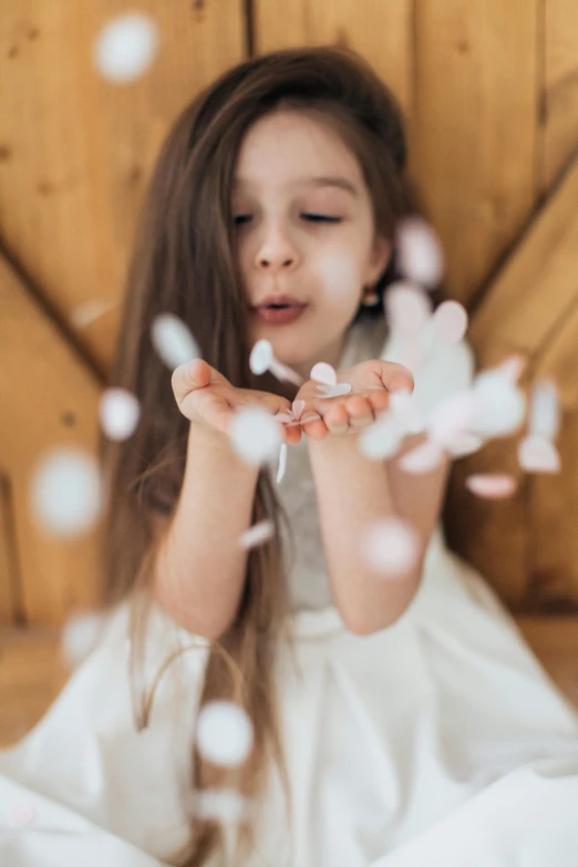 little girl in white dress holding bubbles with her hands