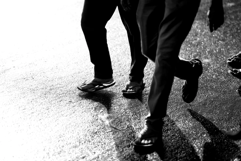 two adults are wearing sandals walking down the street