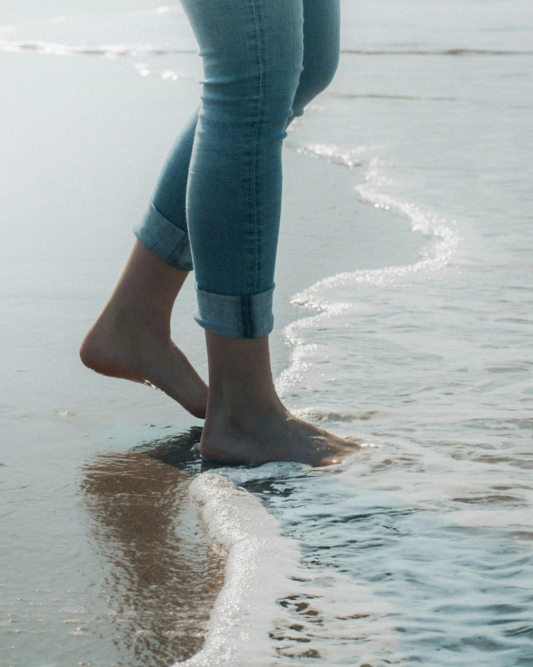 a person walking on the beach with their feet in the water