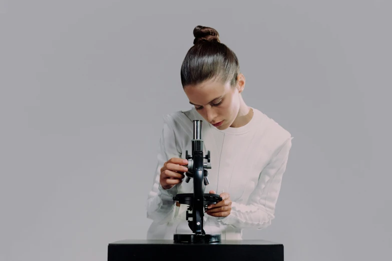 a woman holding a microscope while looking at it