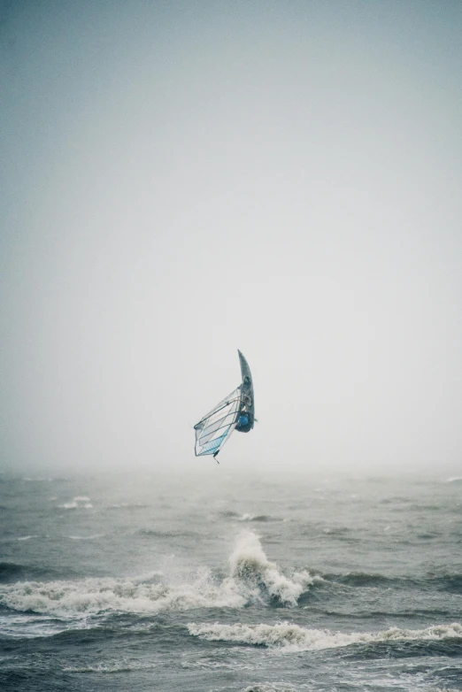 a parasailing in the fog over choppy seas