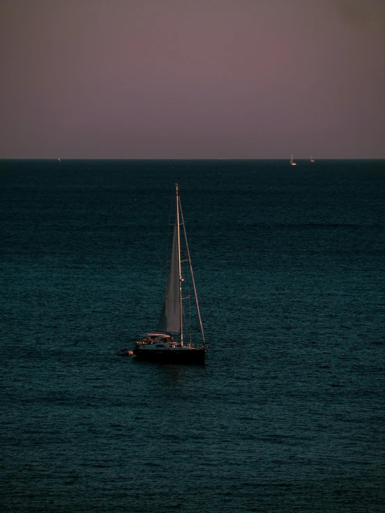 a small sail boat in the middle of the ocean