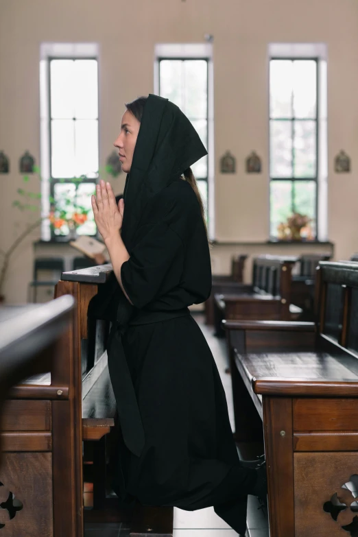 woman in dark robe sitting in church during pray