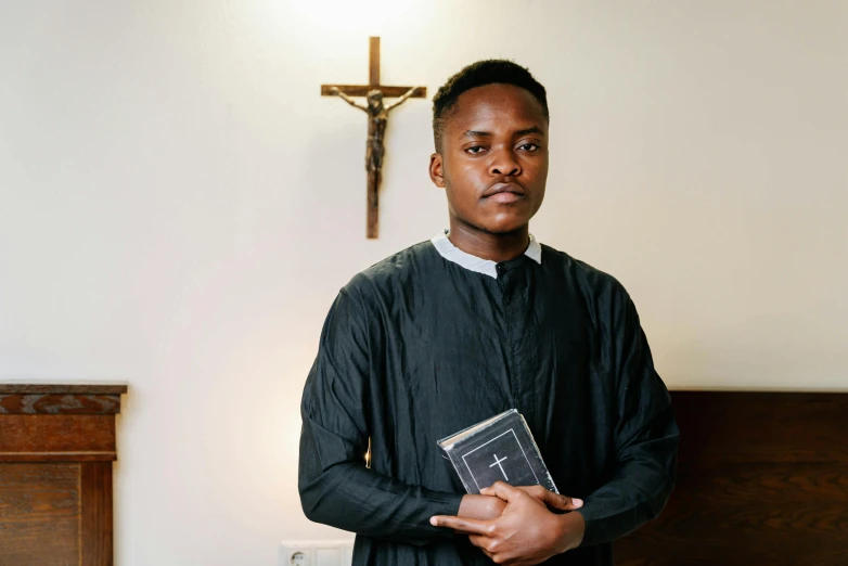 a male priest in black is holding his bible