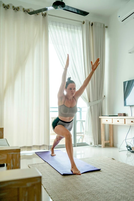 a woman in a yoga position in front of a window