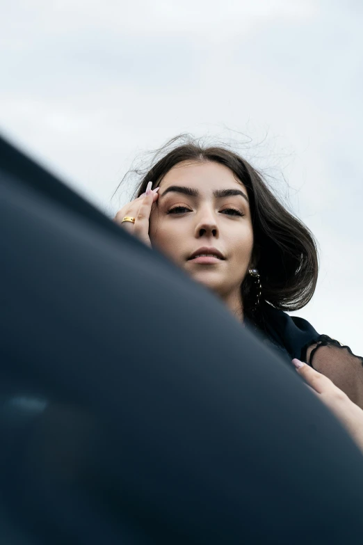 a young woman leaning on her car holding her head in front of her eyes