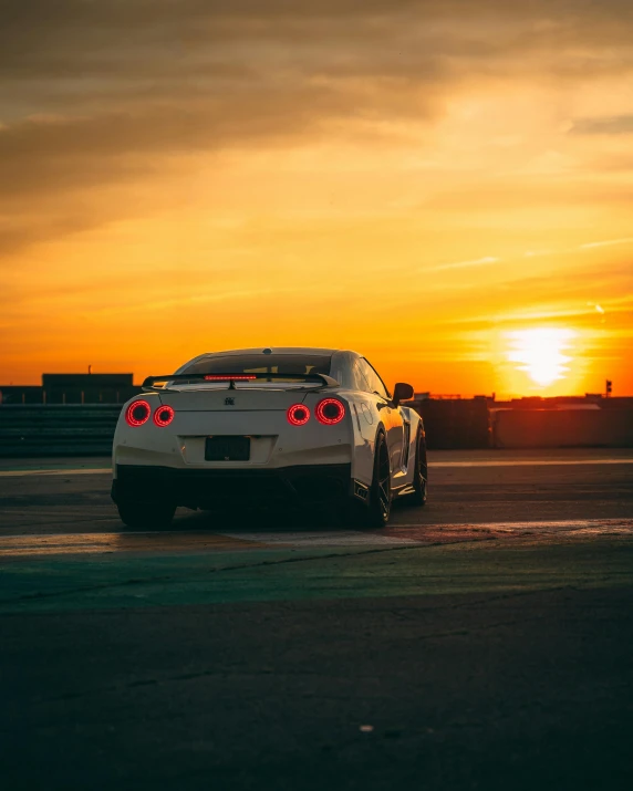a white car driving past a sunset on a track