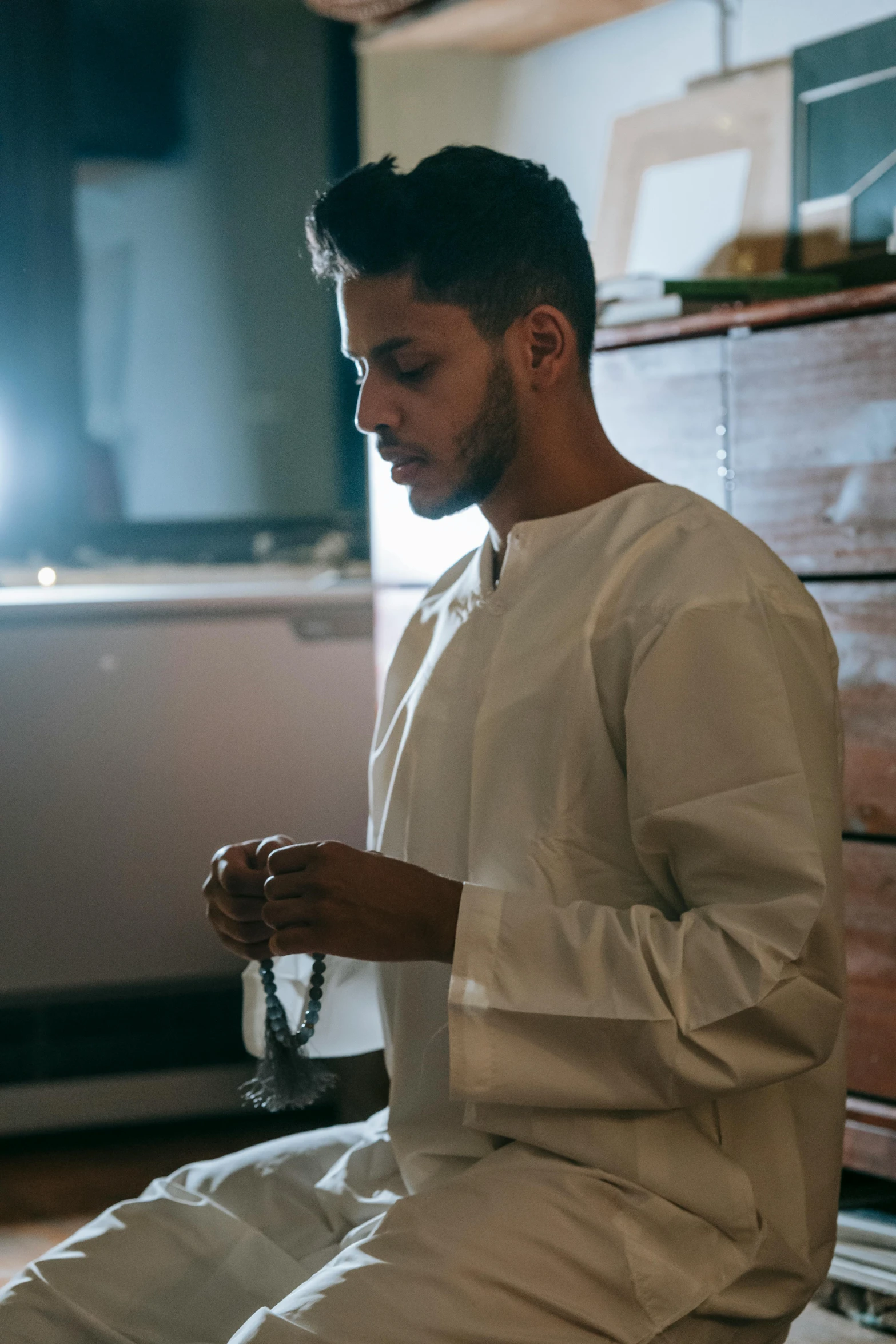 a man in white clothes looking down at his phone