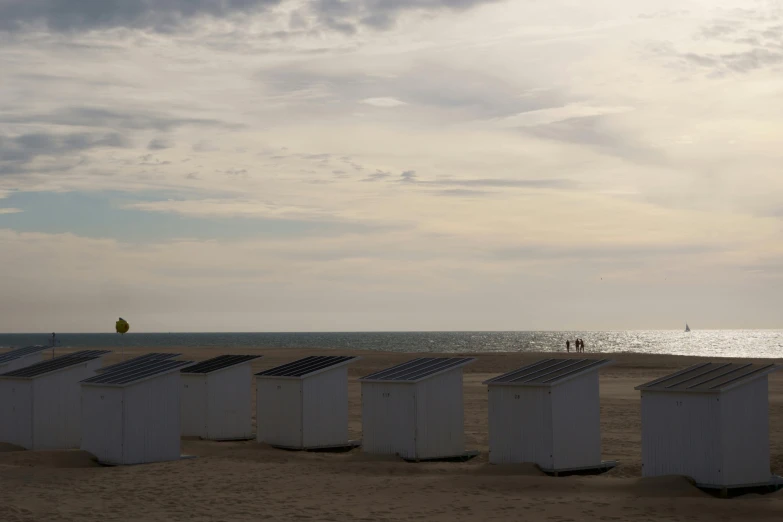 several portable toilets are lined up in the sand