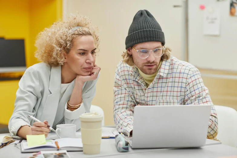 two people with glasses on sitting in front of a laptop