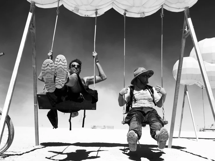 a woman and man sitting on swings near some balloons