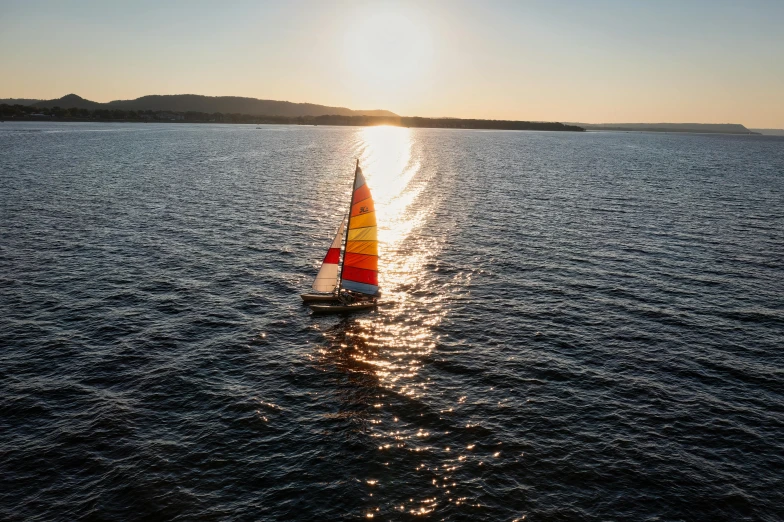 a sailboat sailing through the water with a sunset