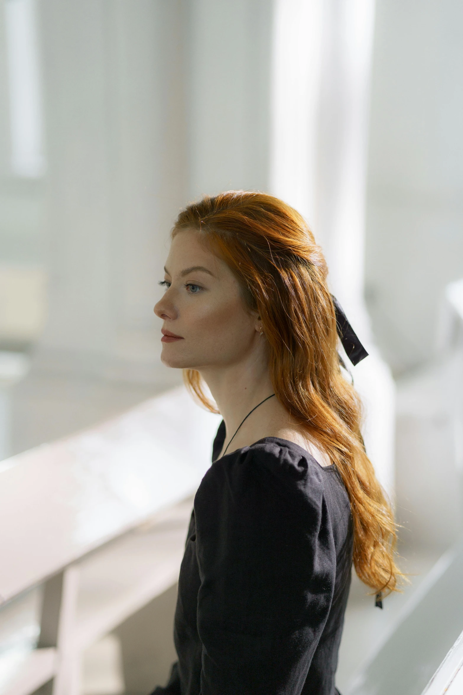 a red haired woman with long hair and a black shirt sitting on a bench