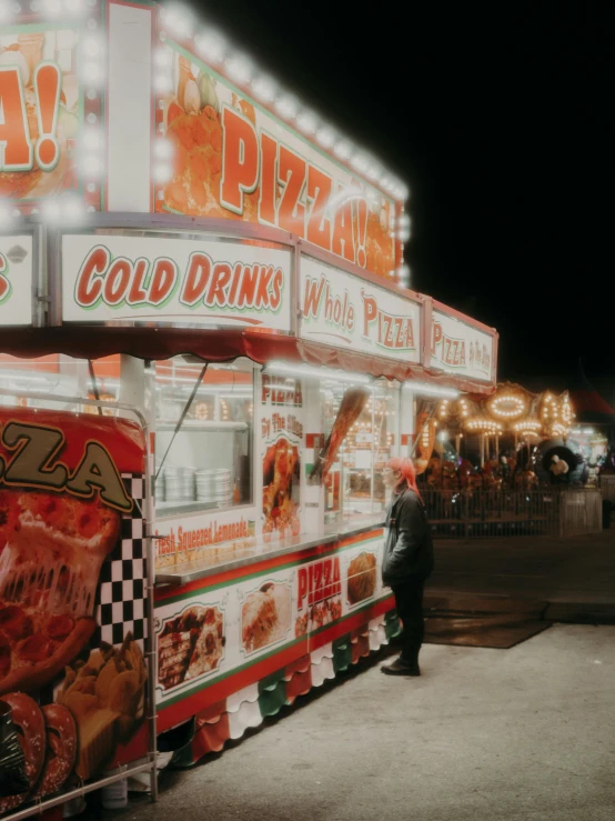 people at a food stand that has many kinds of pizzas