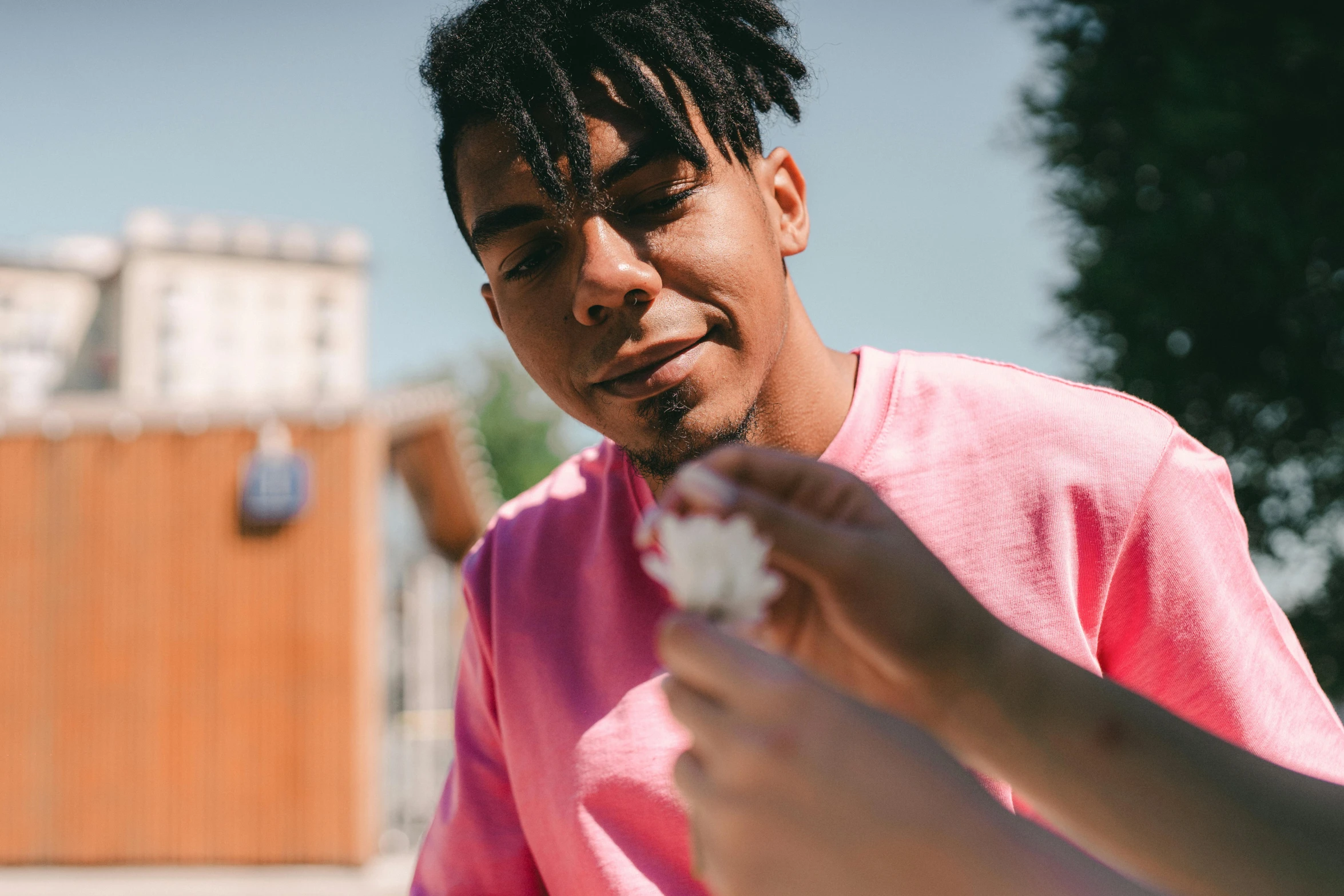 a man holding flowers as he eats soing with his hands