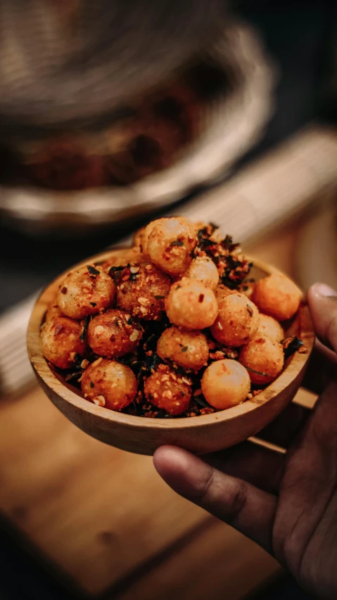 a hand holding up a bowl with food on it