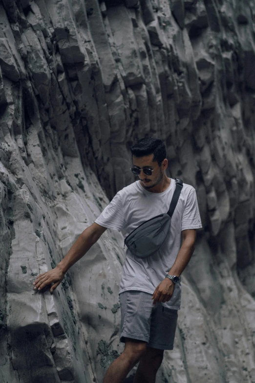 man climbing up a steep side on a rock