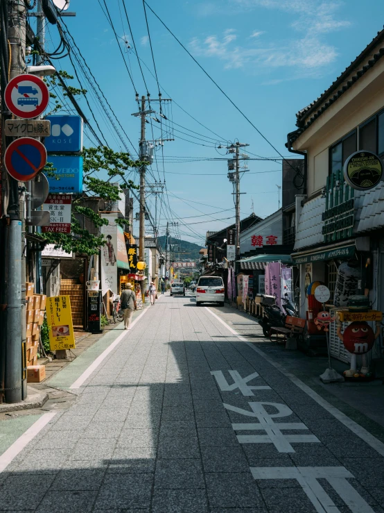 people walking down a small city street by an assortment of shops