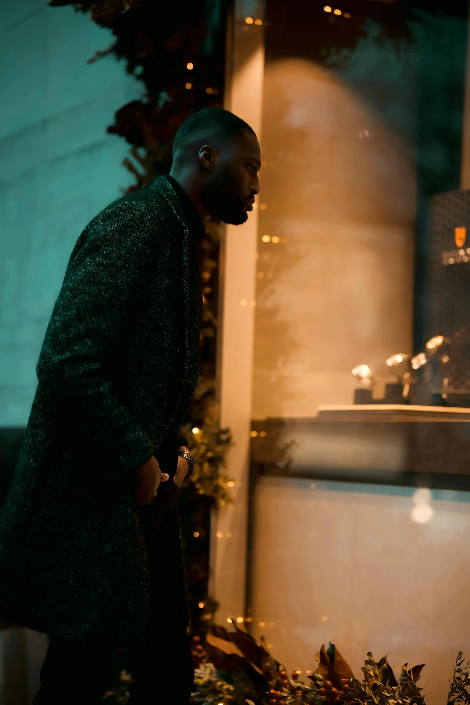 the man is standing by the christmas tree looking down