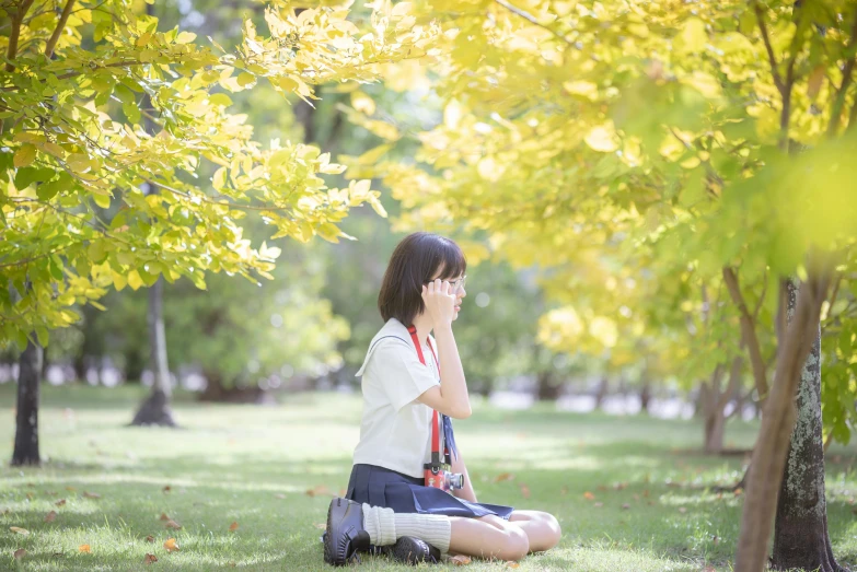 a girl talking on her cellphone while sitting in the park