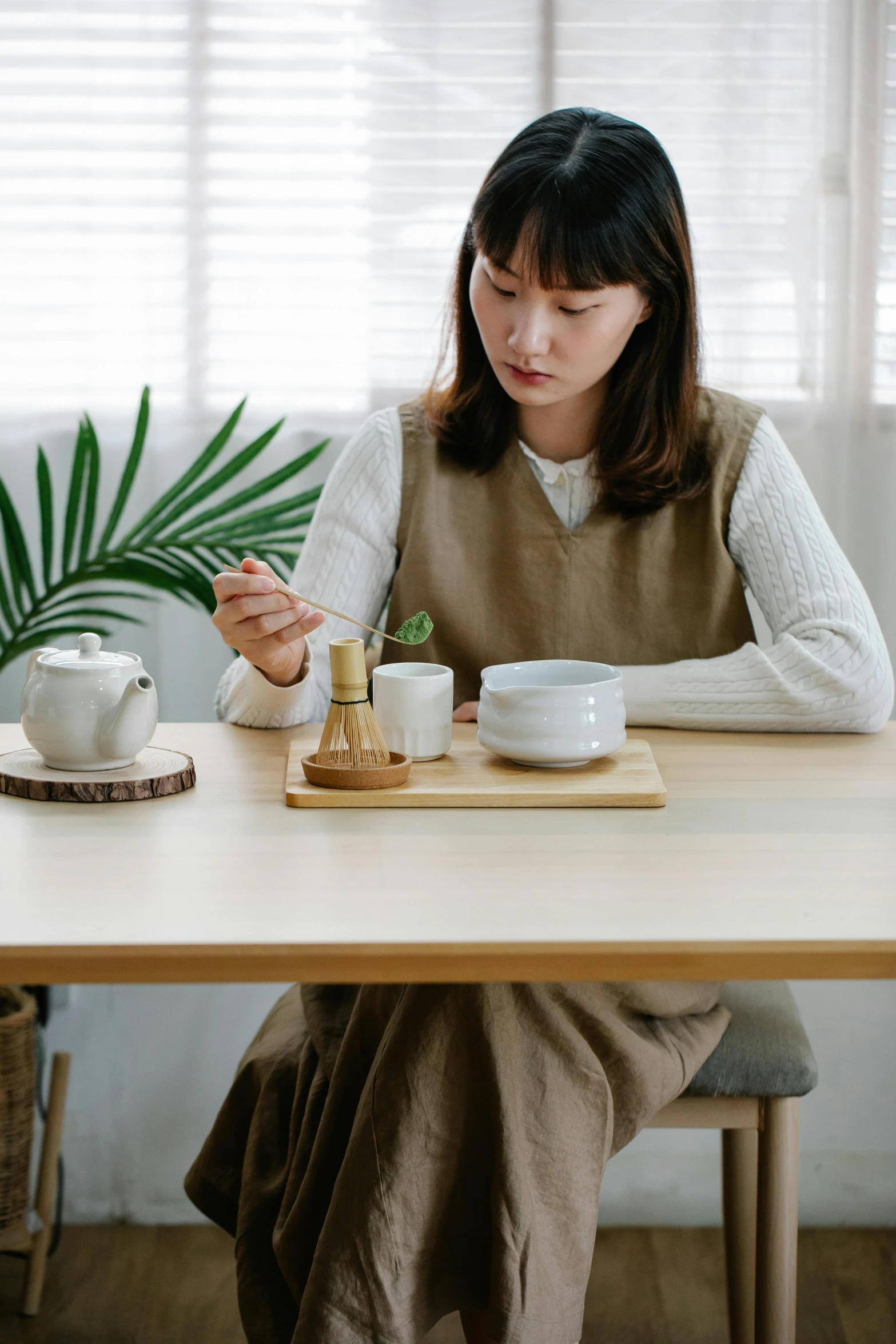 an asian woman sitting at a table, holding a phone