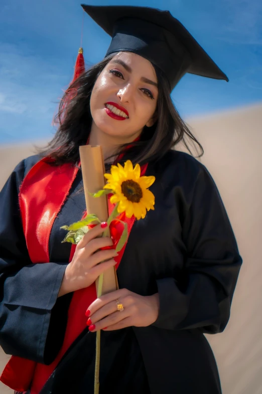 a woman in graduation cap and gown holding flowers