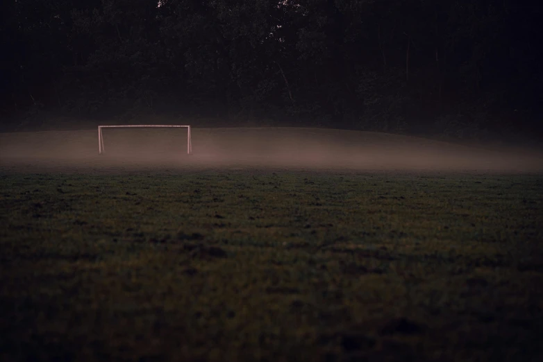 an empty soccer field with some fog coming in from the goal