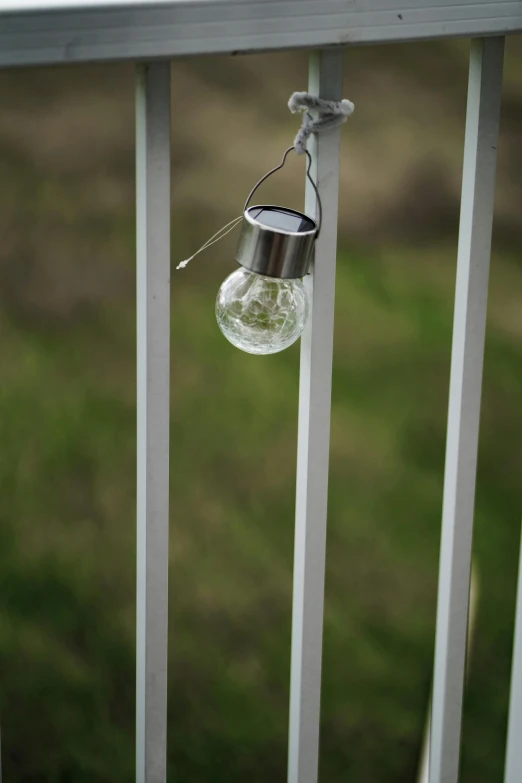 a light bulb and a metal holder hanging from the side of a railing