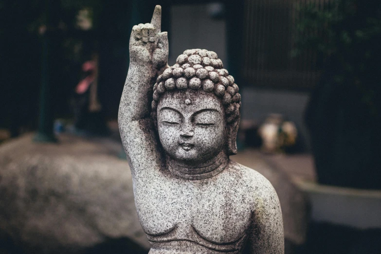 a stone statue of a buddha with its hand in the air