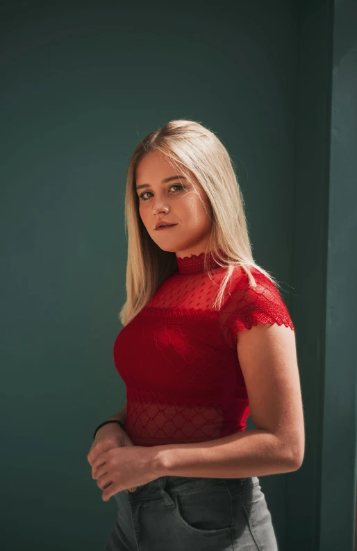 an attractive blonde woman wearing a red top standing