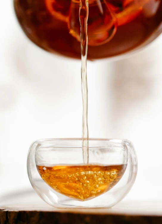 tea being poured into a glass cup and overflowing