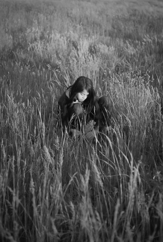 a man sitting in a grassy field reading a book