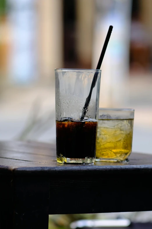 a s of dark liquid in a glass with an straw