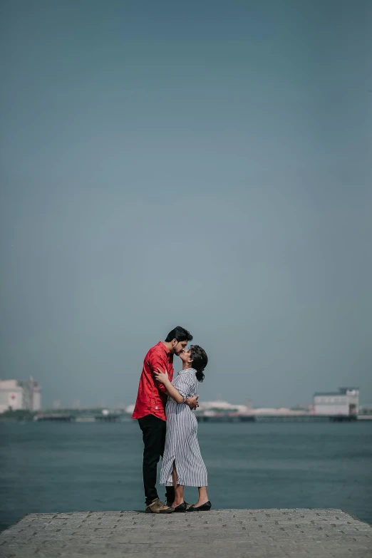 two people standing on top of a pier next to water