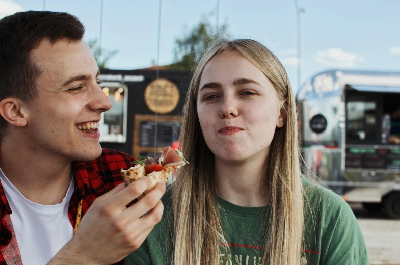 a woman eating food next to a man