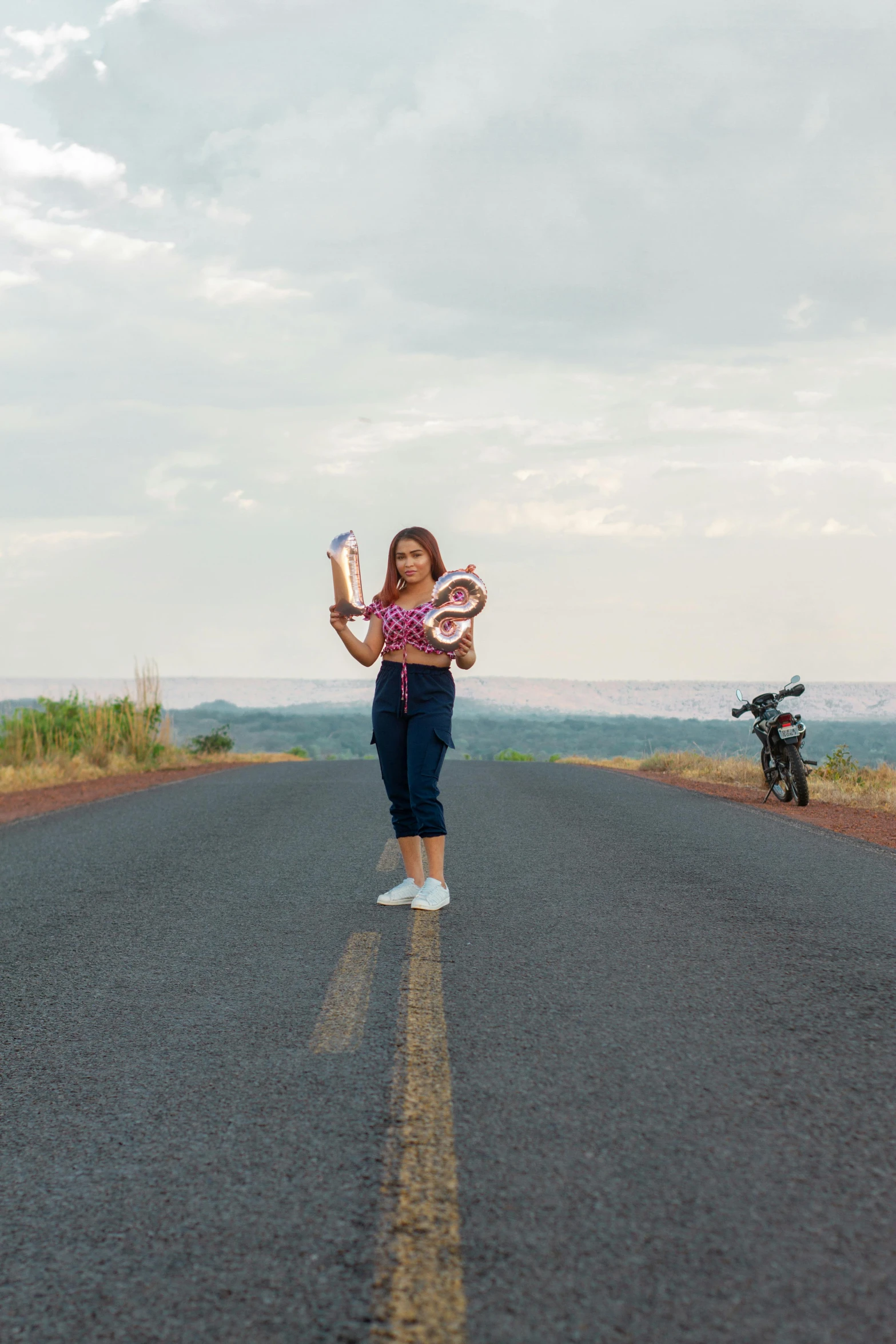 a woman standing in the middle of a road holding up a glove