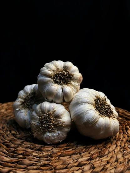 three garlic clumps are piled on a basket