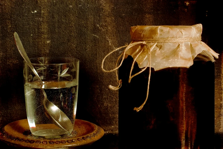 a jar filled with liquid next to a glass with a spoon