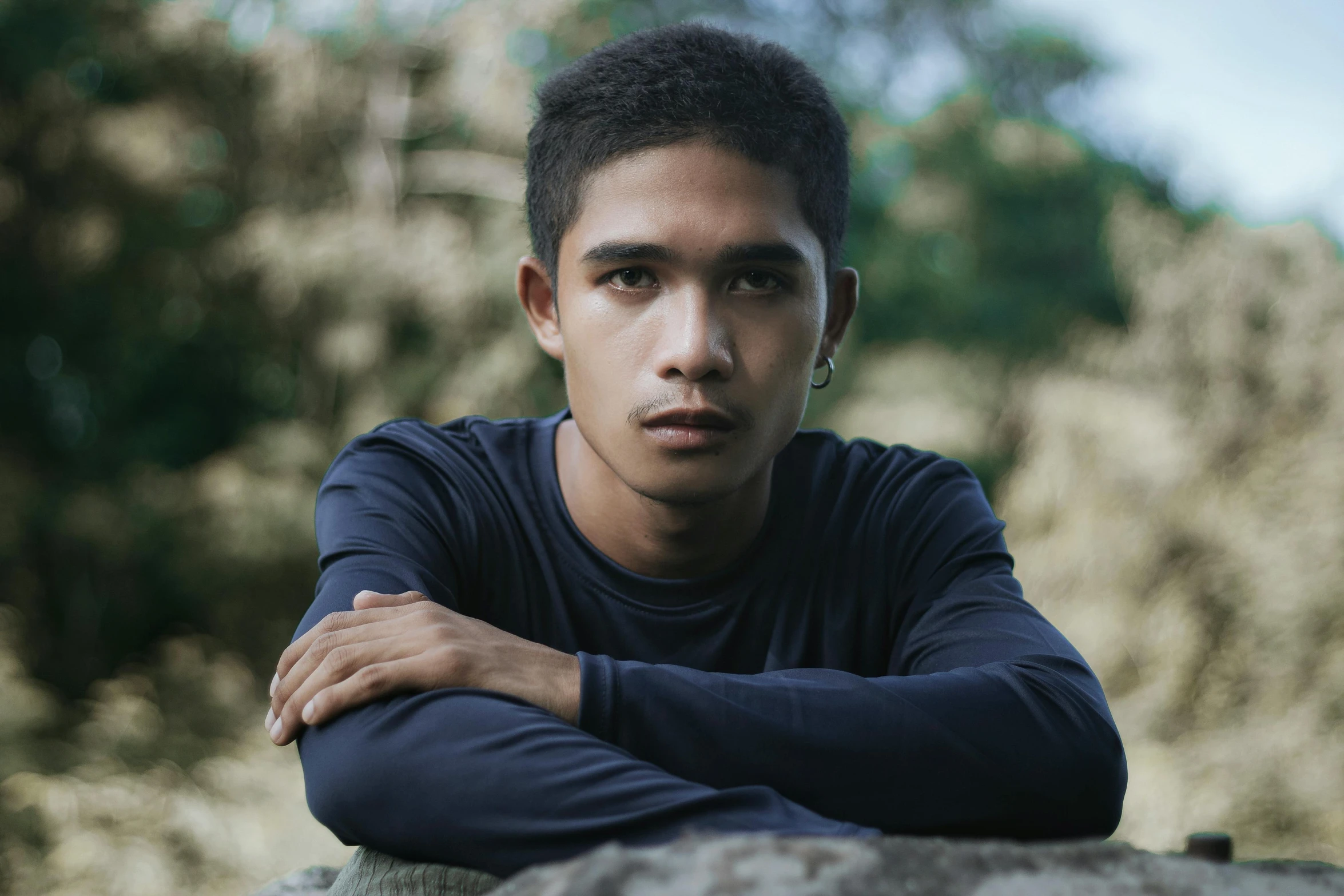 a man with his arms crossed leaning on some rocks