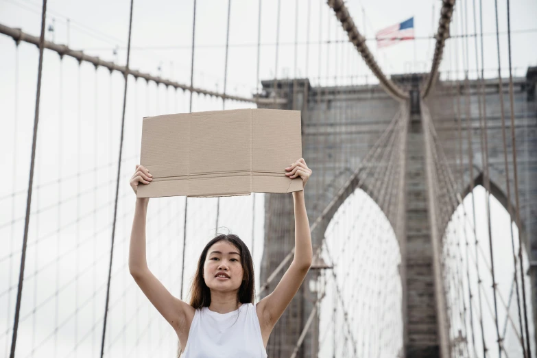 a girl holding up a cardboard sign over her head