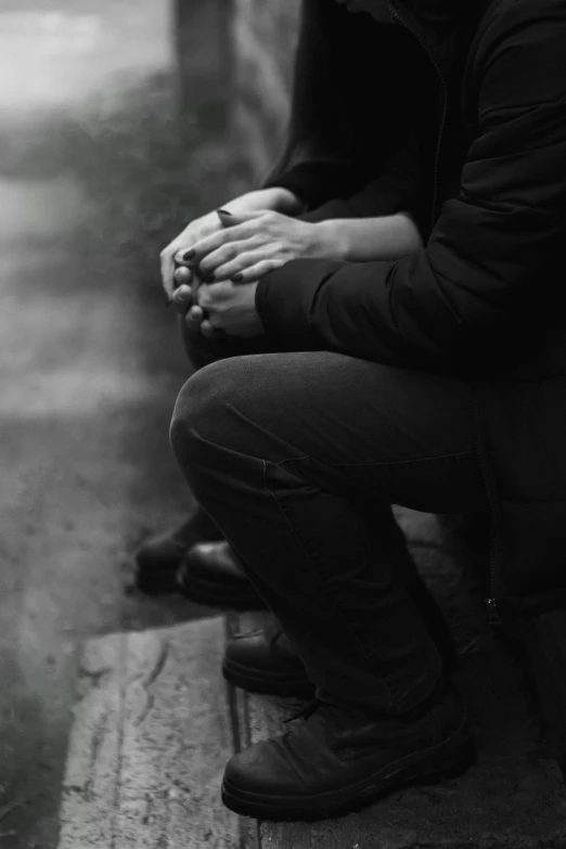 a person sitting on a bench with their hands clasped