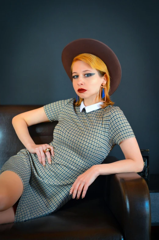 the woman is posing on a chair wearing a hat