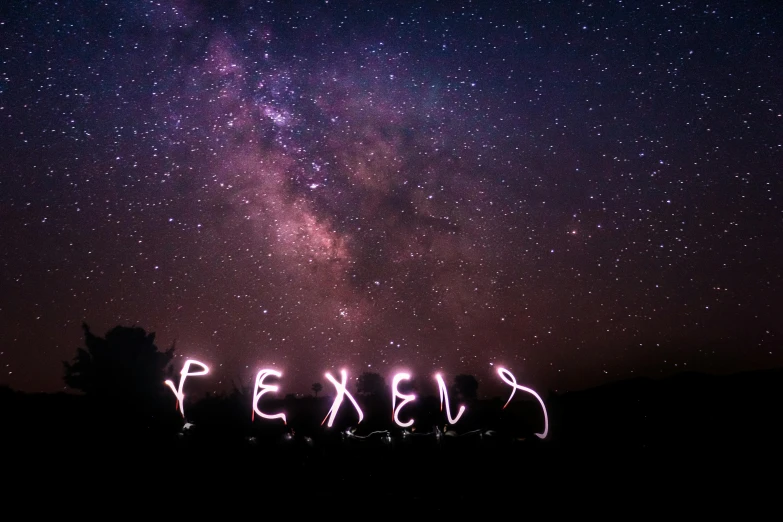 the stars in the sky above some trees and some light lettering