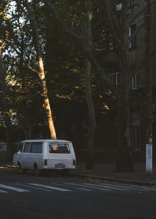 a white van parked in the street by some trees