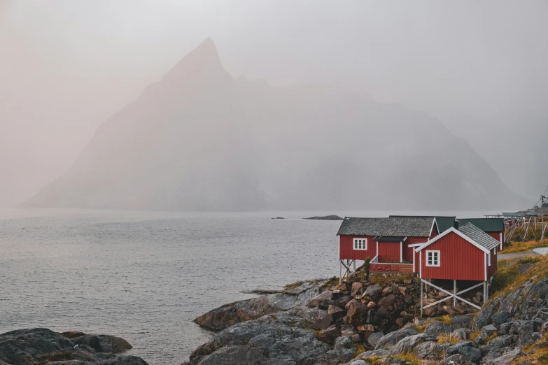 a red house sitting next to some rocks near the ocean