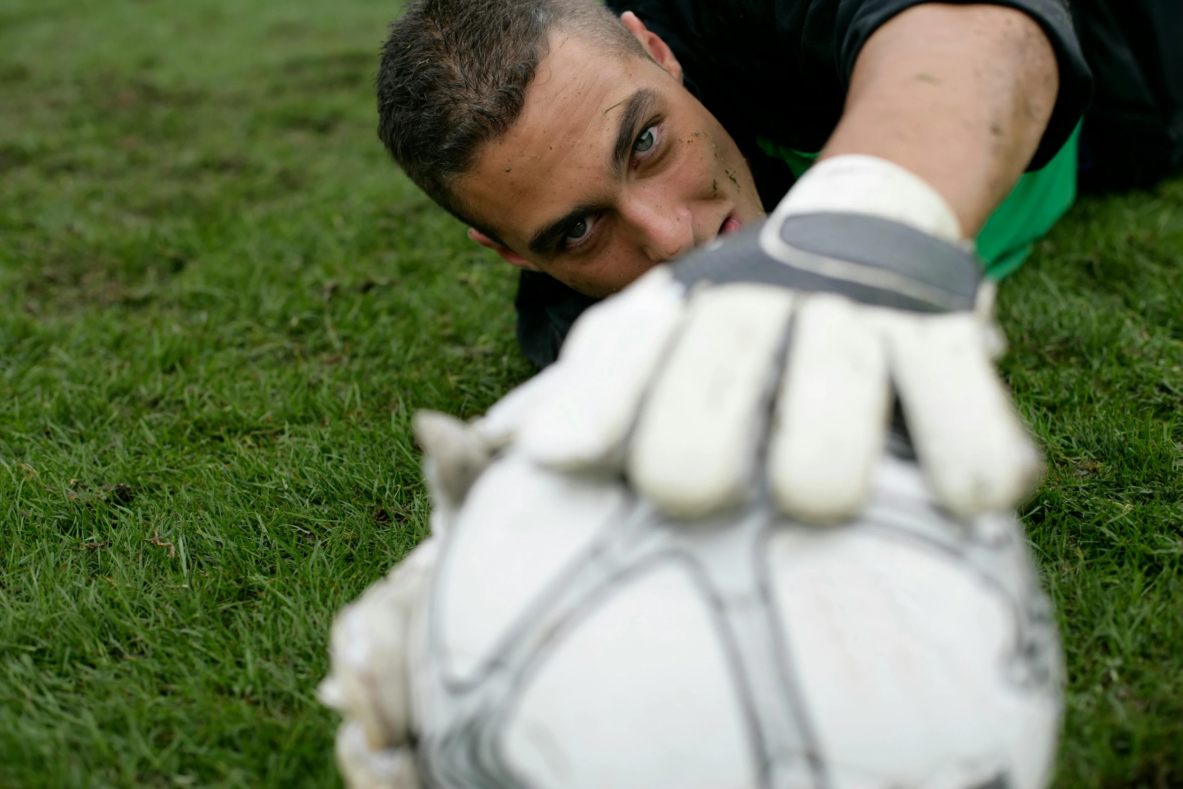 a man in a green field holding onto the hand of a white glove