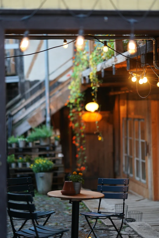 the tables and chairs in the courtyard are covered by lights