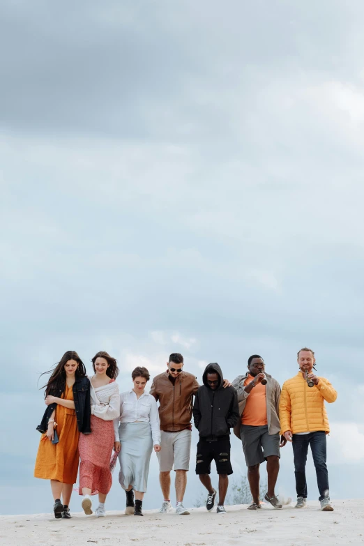 five people standing side by side on the sand